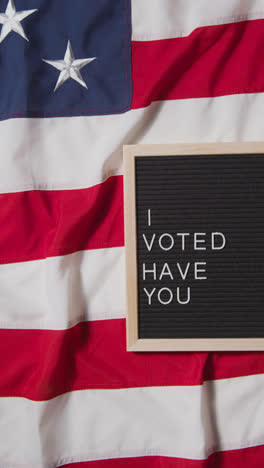 Vertical-Video-Of-Sign-Reading-I-Voted-Have-You-Lying-On-US-Stars-And-Stripes-Flag-For-American-Election-2024-2